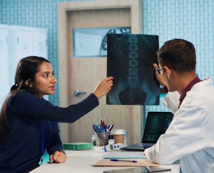 Indian general practitioner and nurse examine hospital records and x ray tests, finding diagnosis for a patient. Medical staff reviewing scans and doing healthcare reports with expertise. Camera A.